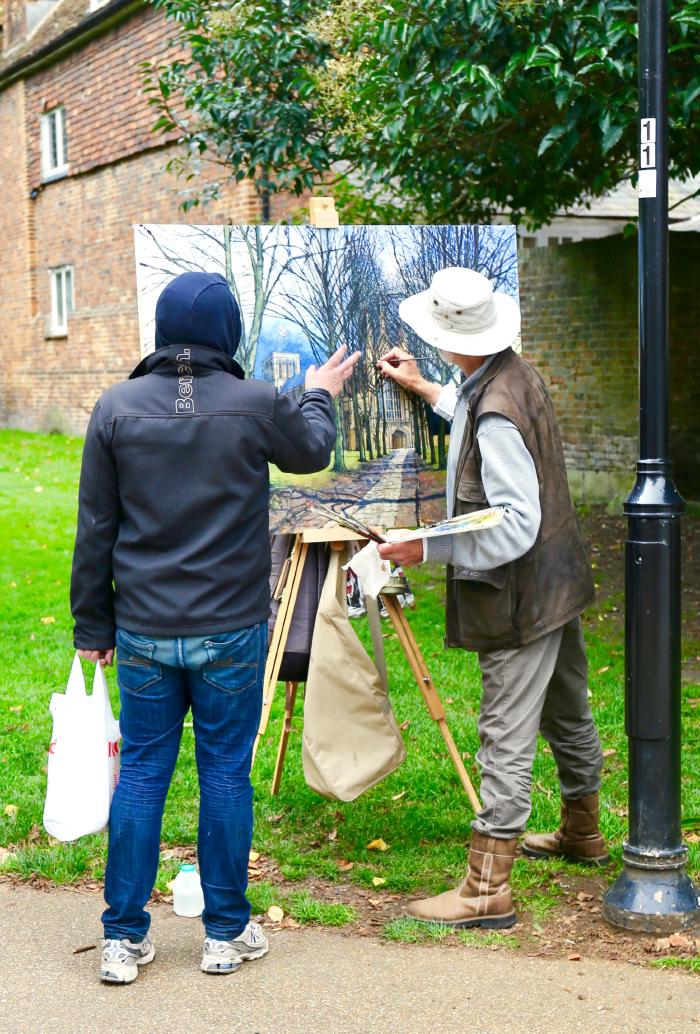 Two non-squirrel-people in a greened-over village pair programming a painting together